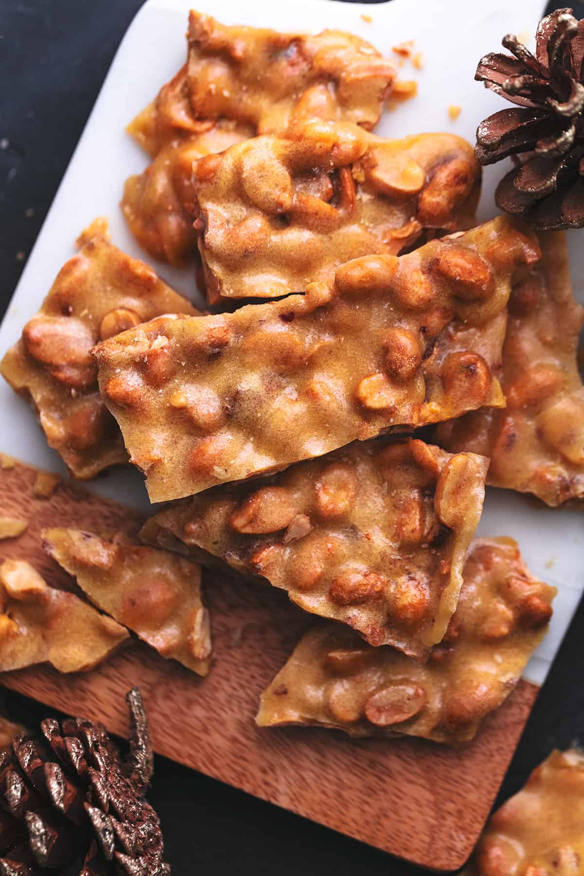 peanut brittle pieces on a cutting board with festive pinecones