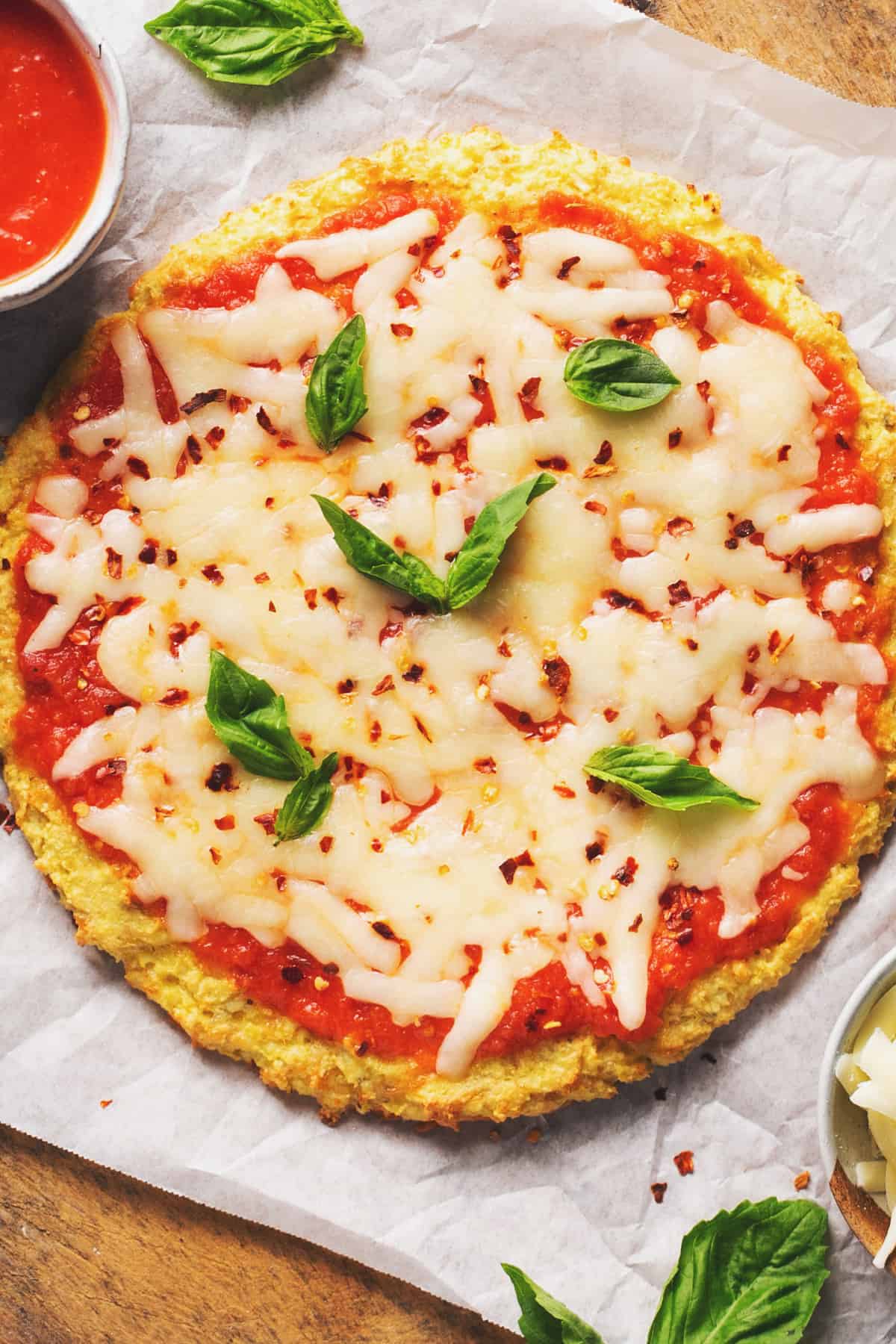 whole cauliflower crust pizza on wooden cutting board