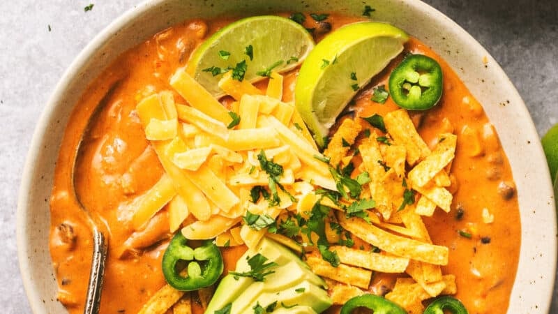 overhead view of enchilada soup in bowl with lime wedge and jalapeno slices