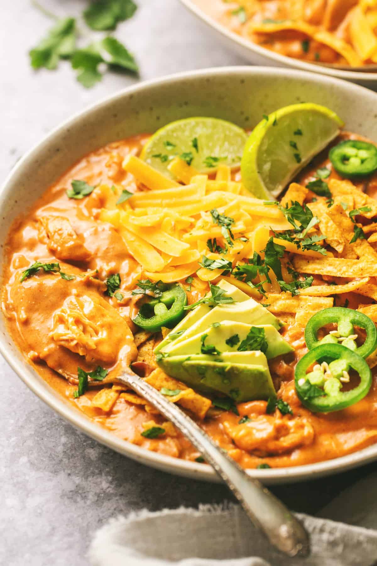 creamy enchilada soup in a bowl with jalapeno slices and lime wedge