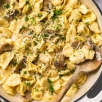 cheese tortellini pasta in skillet with wooden serving spoon