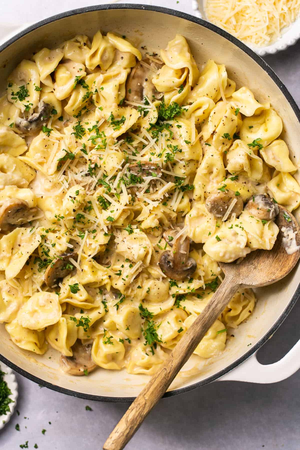 cheese tortellini pasta in skillet with wooden serving spoon