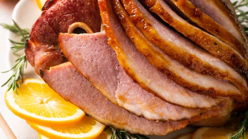 platter of glazed, baked ham on platter with garnishes