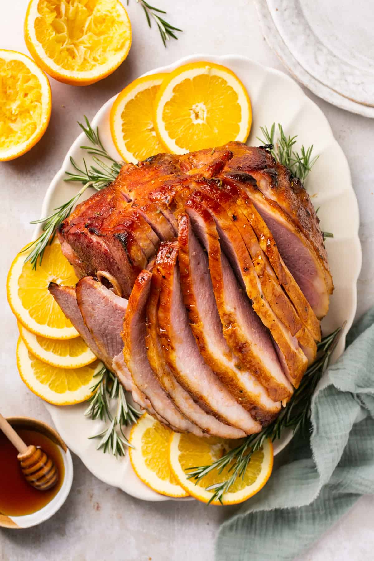overhead view of sliced honey baked ham on platter with orange slices