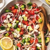 greek salad with tomatoes, onions, and cucumbers in a bowl