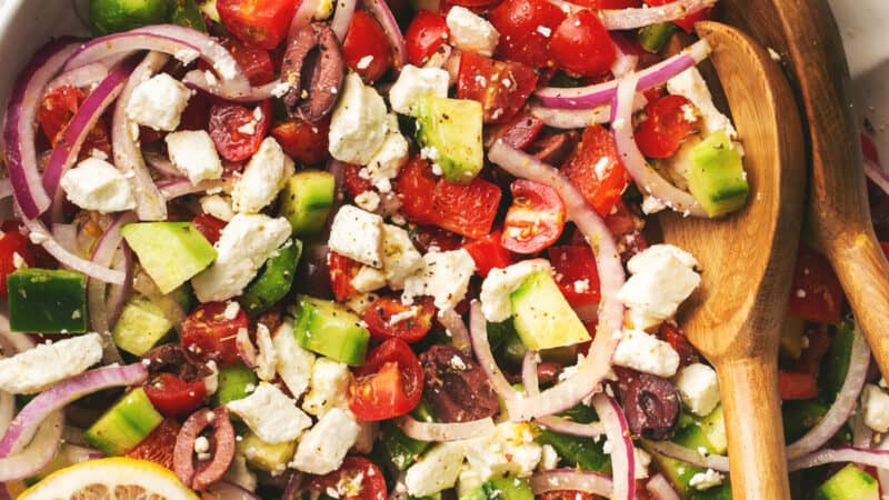 greek salad with tomatoes, onions, and cucumbers in a bowl