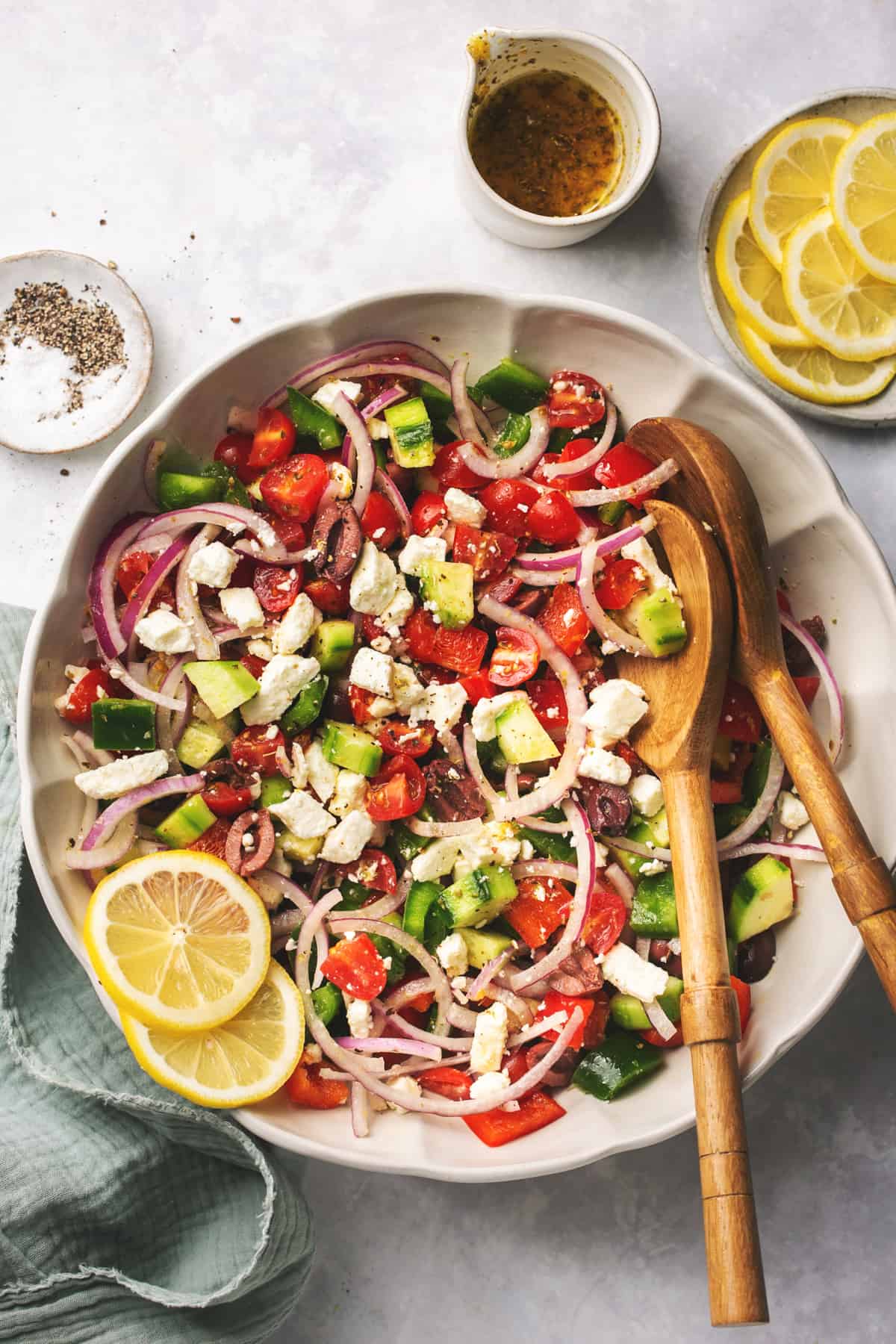 bowl of mediterranean salad with serving spoons and ingredient dishes