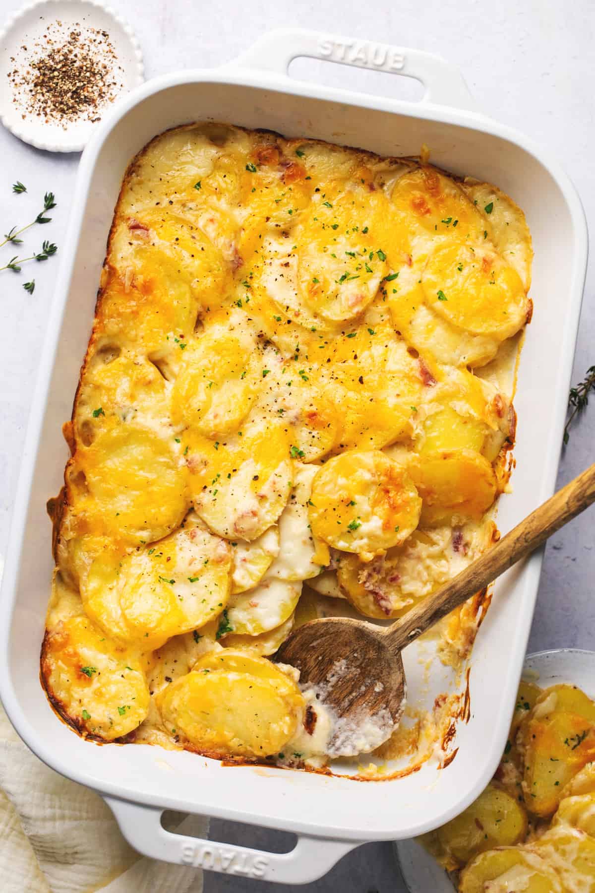 serving spoon scooping potatoes with cheese in baking dish