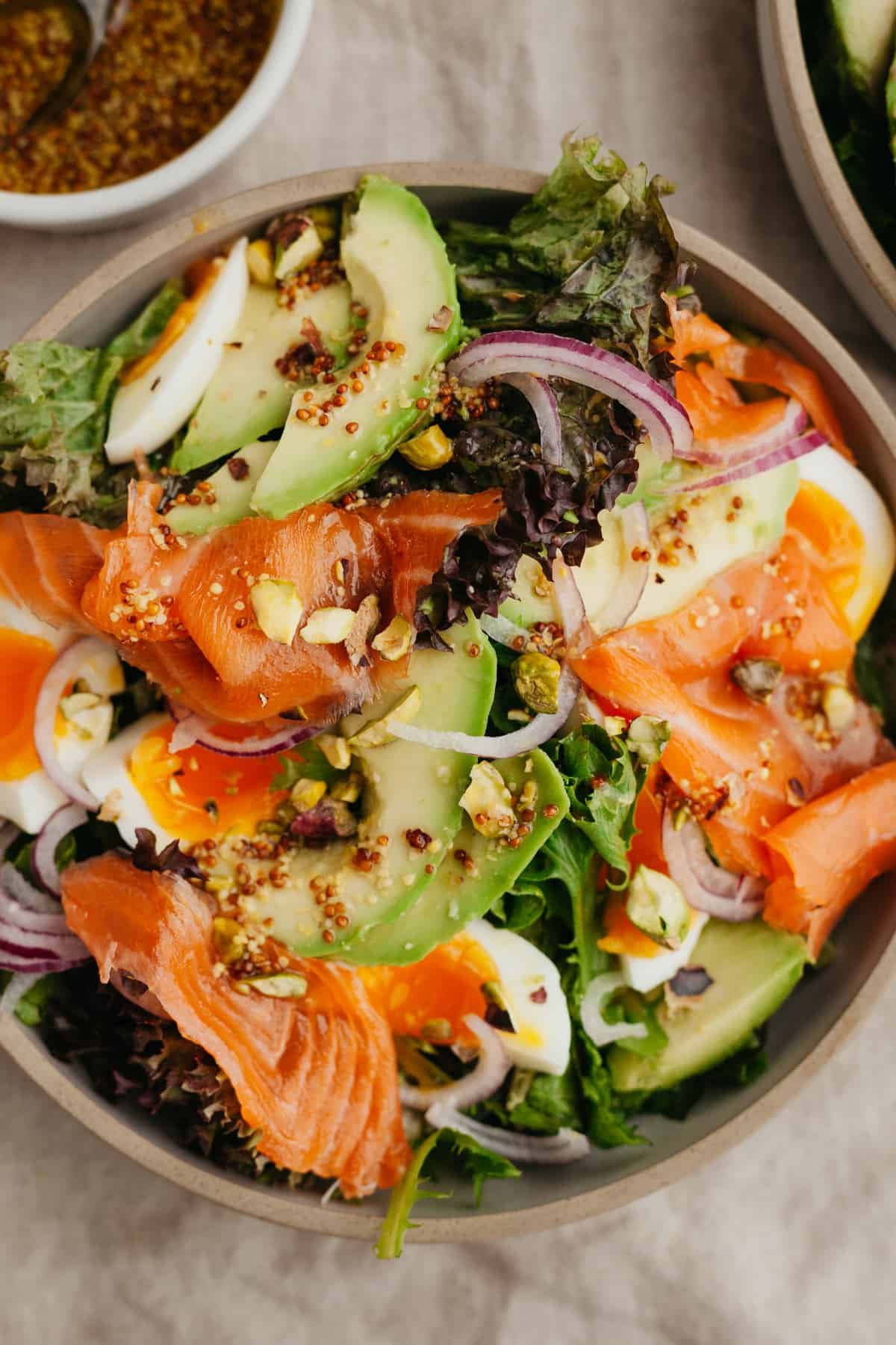 smoked salmon salad in a bowl with dressing in another bowl