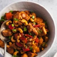 bowl of rice topped with cashew chicken and fork on side