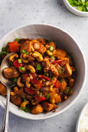 bowl of rice topped with cashew chicken and fork on side