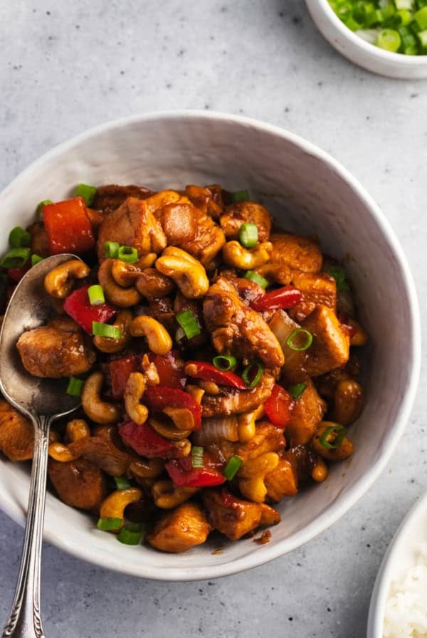bowl of rice topped with cashew chicken and fork on side