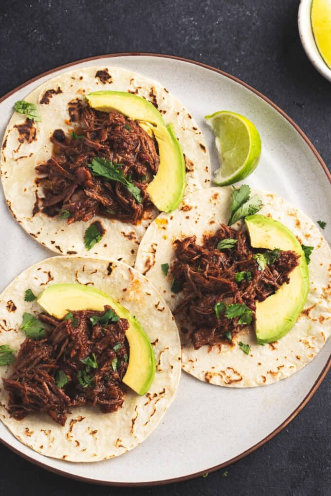 three shredded beef tacos on a platter