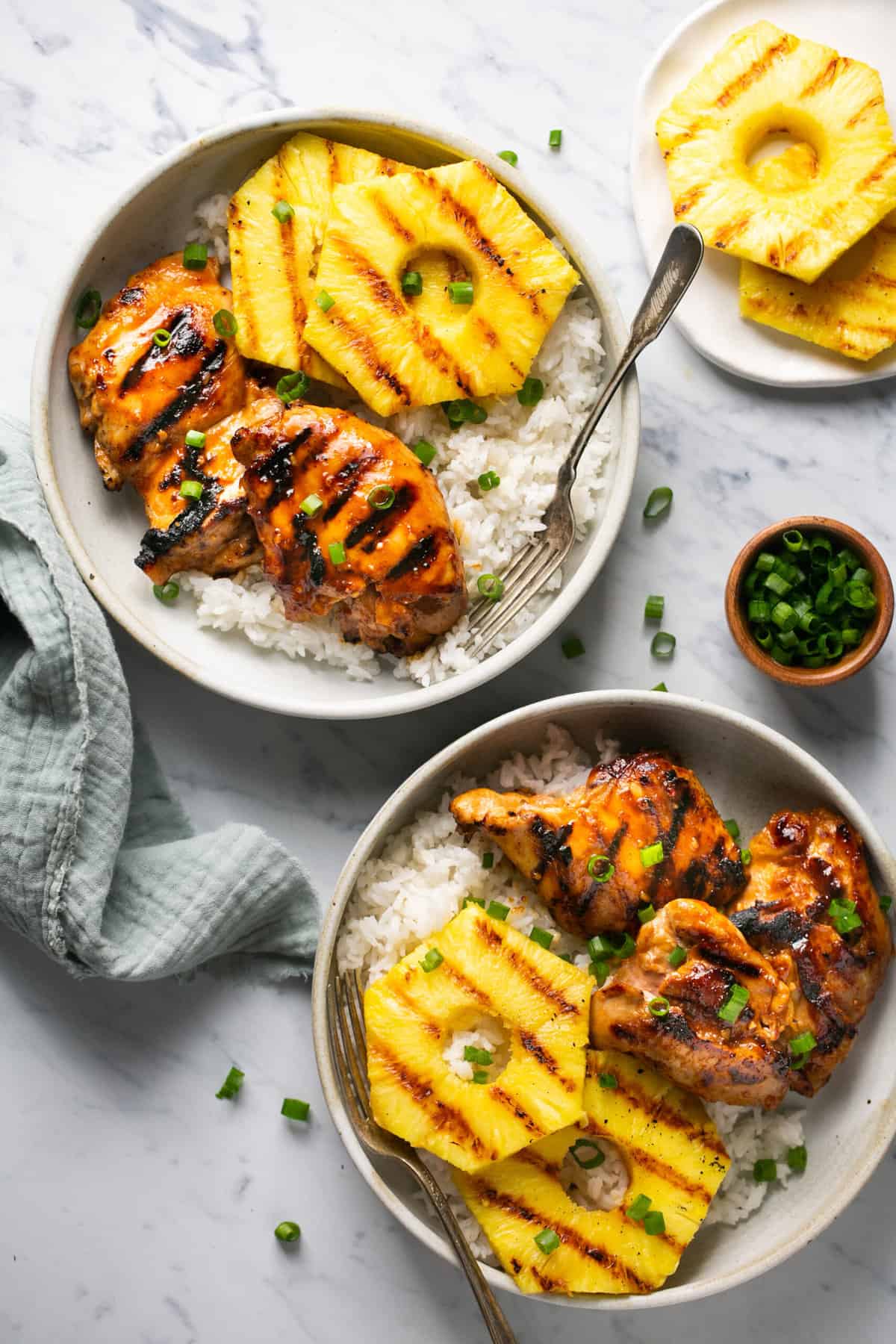 two plates of huli huli chicken with pineapple and fork