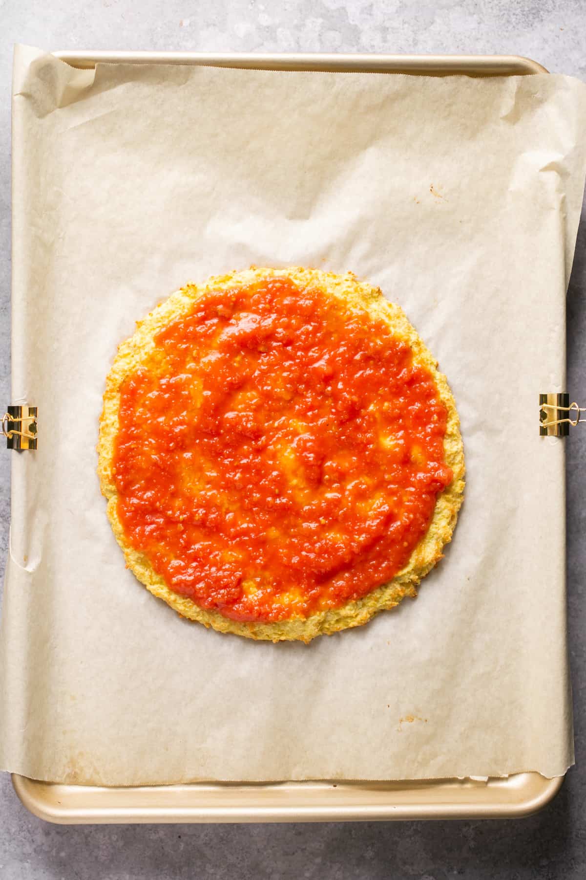 pizza sauce spread on a cauliflower crust