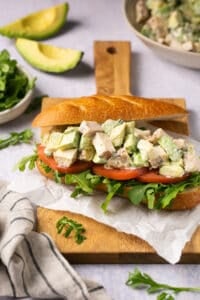 chicken salad on sub roll on a wooden cutting board