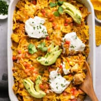 casserole dish with cheesy chicken casserole, avocado, and sour cream toppings