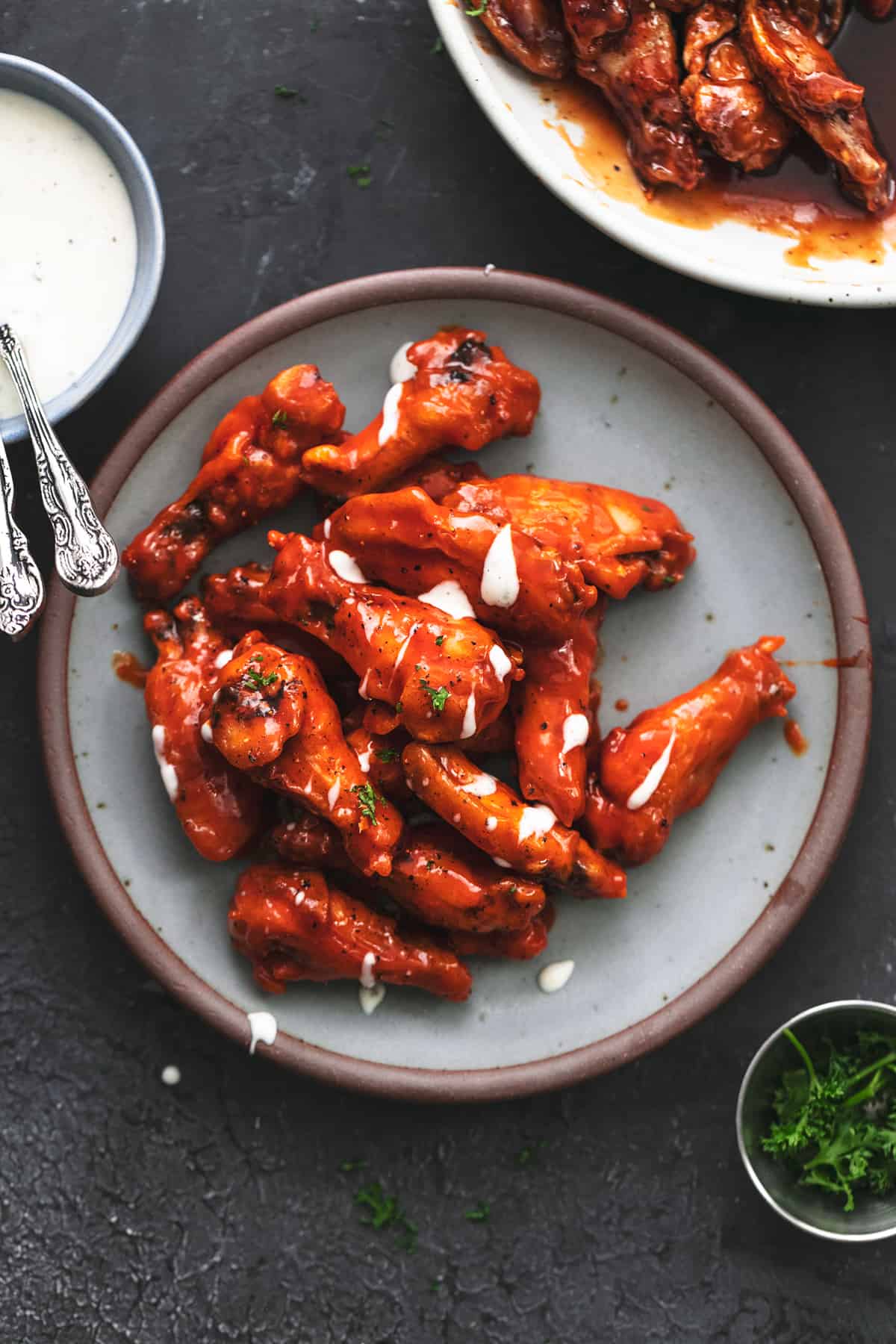 overhead view of platter of chicken wings with bowl of ranch dressing and chopped parsley
