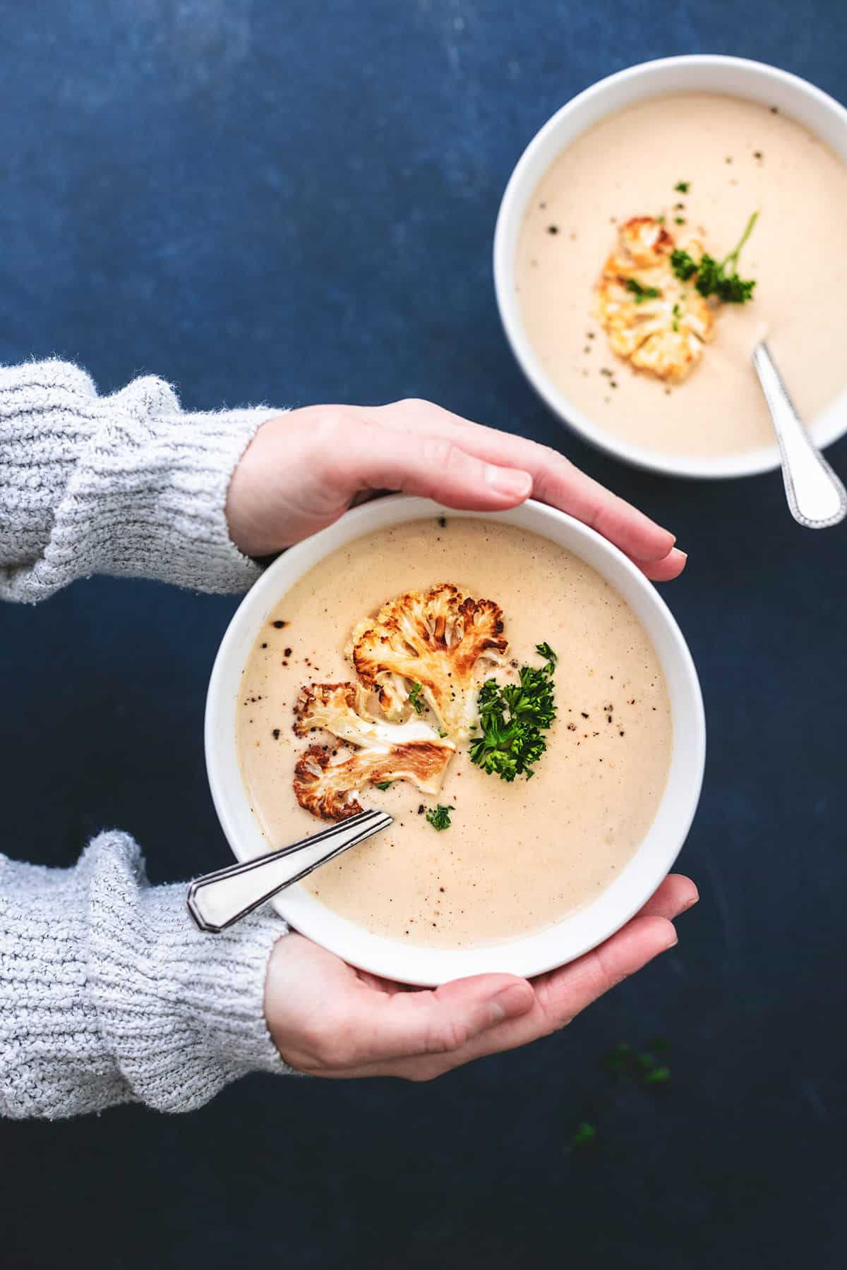 hands bolding bowl of roasted cauliflower soup