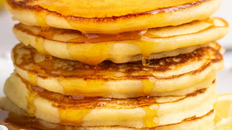 up close stack of pancakes with syrup dripping