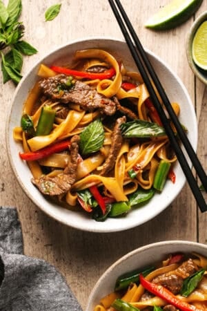bowl of thai noodles with basil and beef with chopsticks