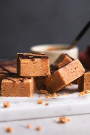 peanut butter fudge pieces stacked on a cutting board