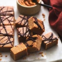 peanut butter fudge pieces on a cutting board with napkin and bowl of peanut butter