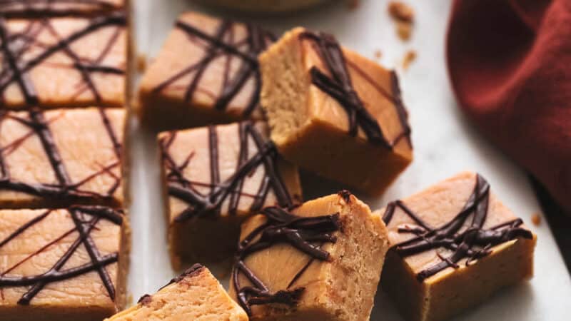peanut butter fudge pieces on a cutting board with napkin and bowl of peanut butter