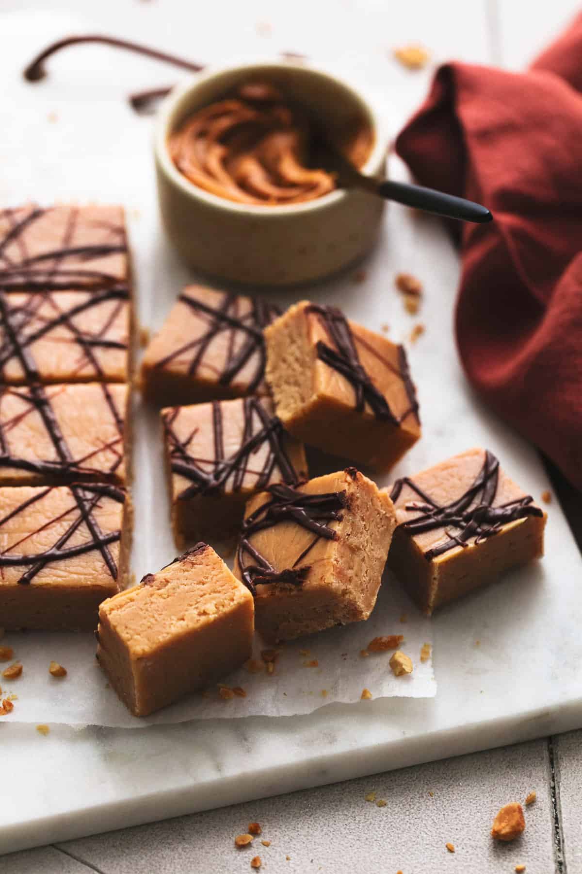 peanut butter fudge pieces on a cutting board with napkin and bowl of peanut butter