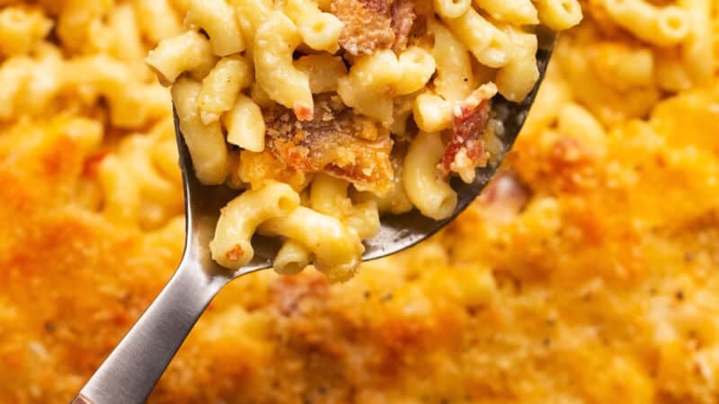 serving spoon scooping mac and cheese with bacon