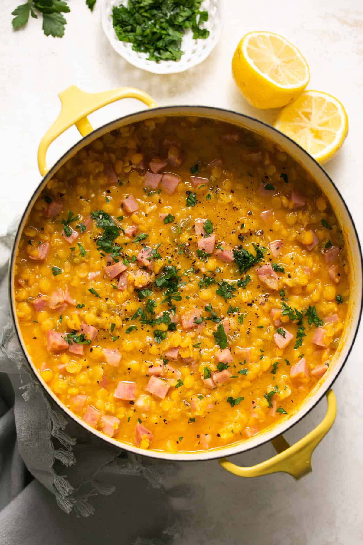 pot of soup with split peas and diced ham with herb garnish