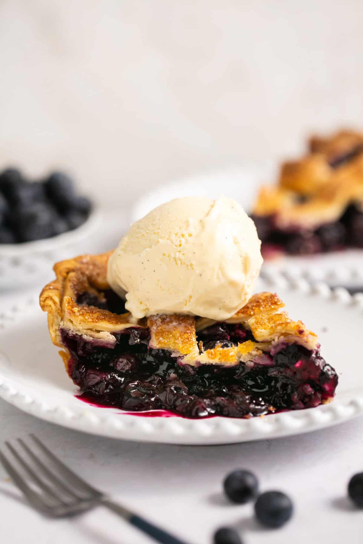 slice of blueberry pie topped with vanilla ice cream