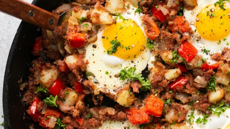 beef and potatoes with veggies and fried eggs on top