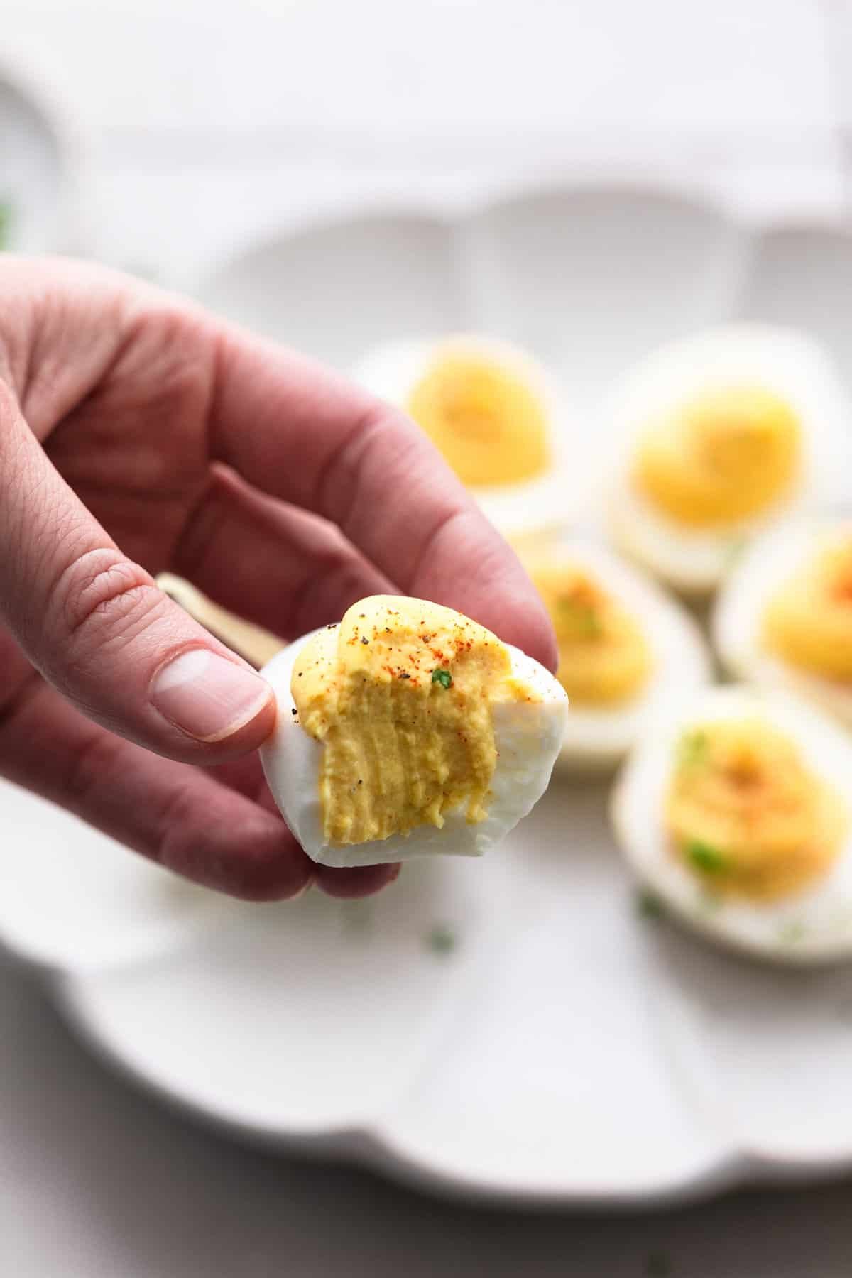 hand holding single deviled egg with bite out