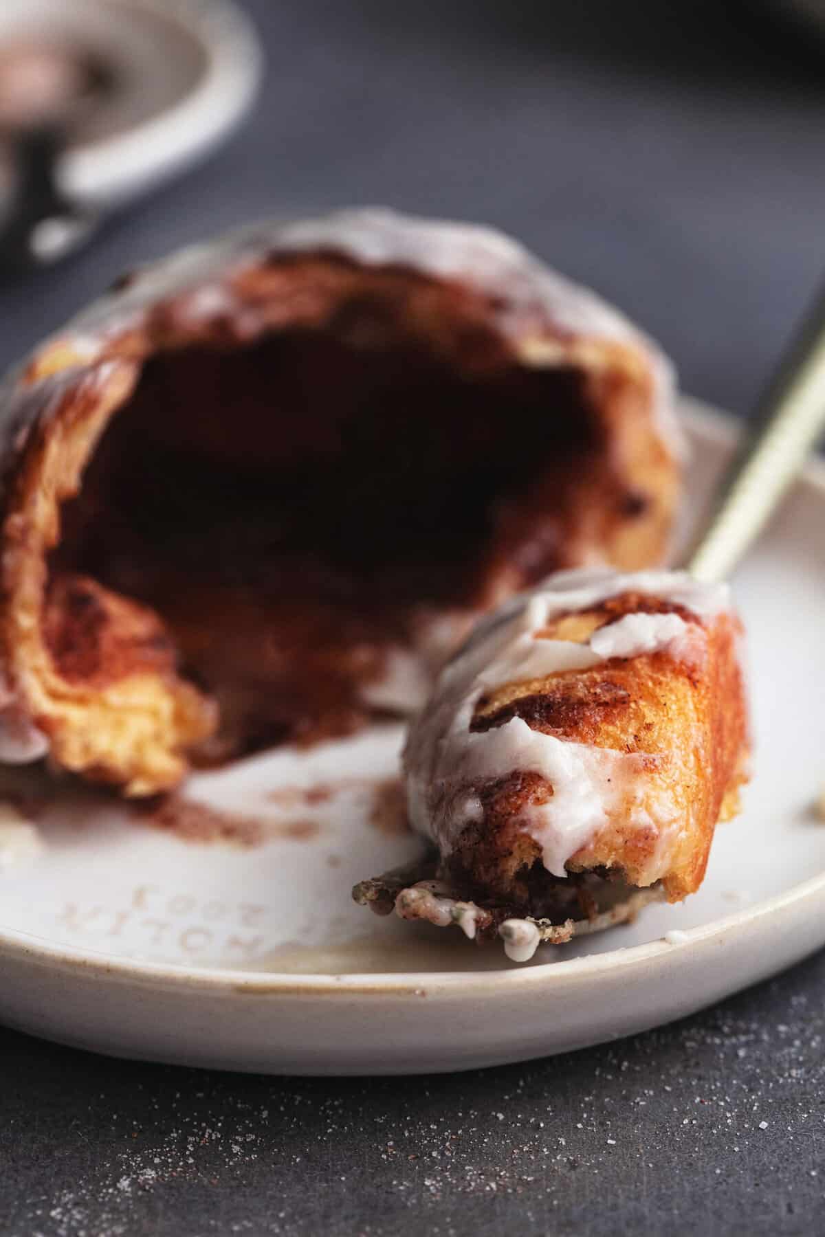 fork cutting out piece of cinnamon bun on plate