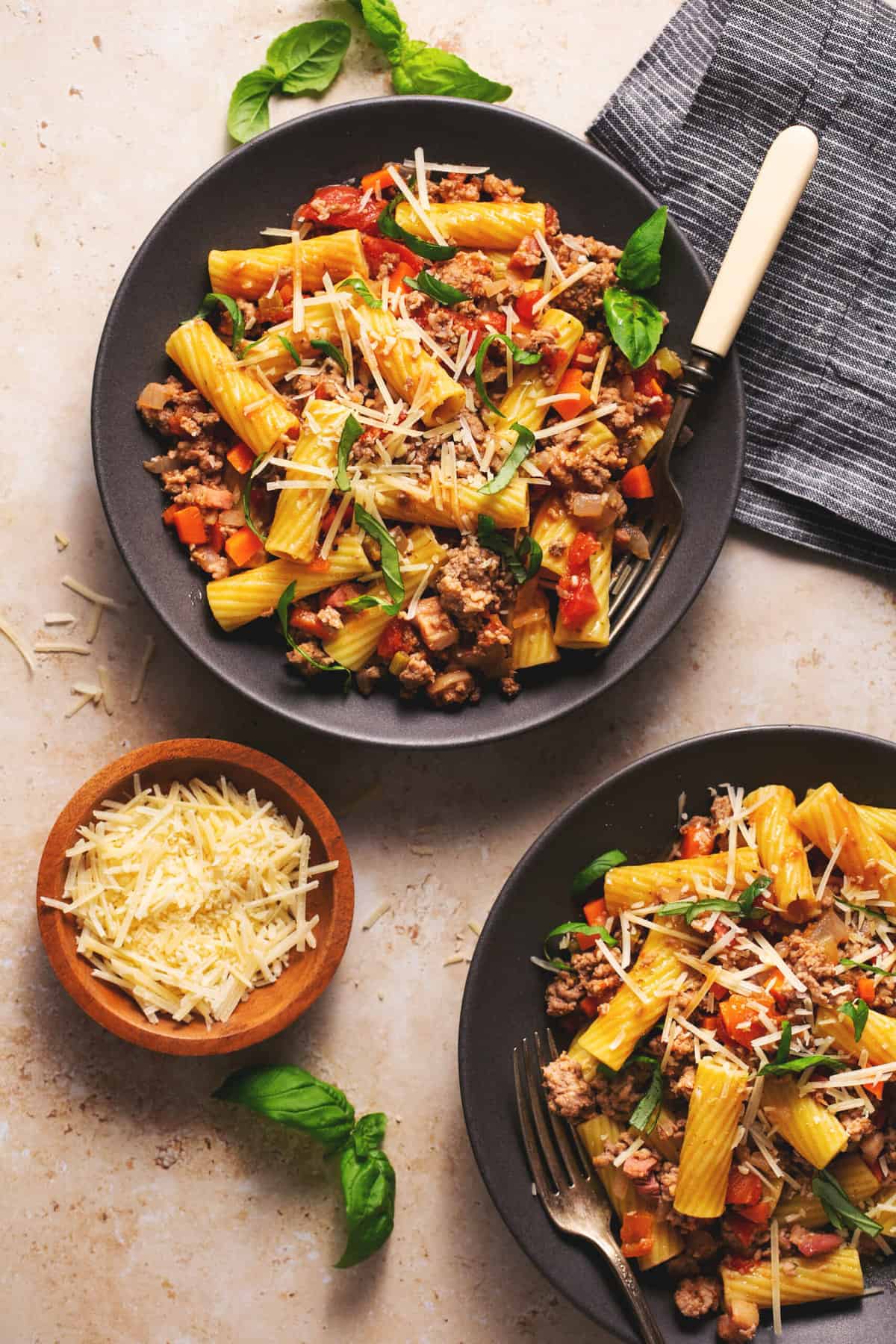 two plates of noodles with beef and pork and parmesan cheese on the side