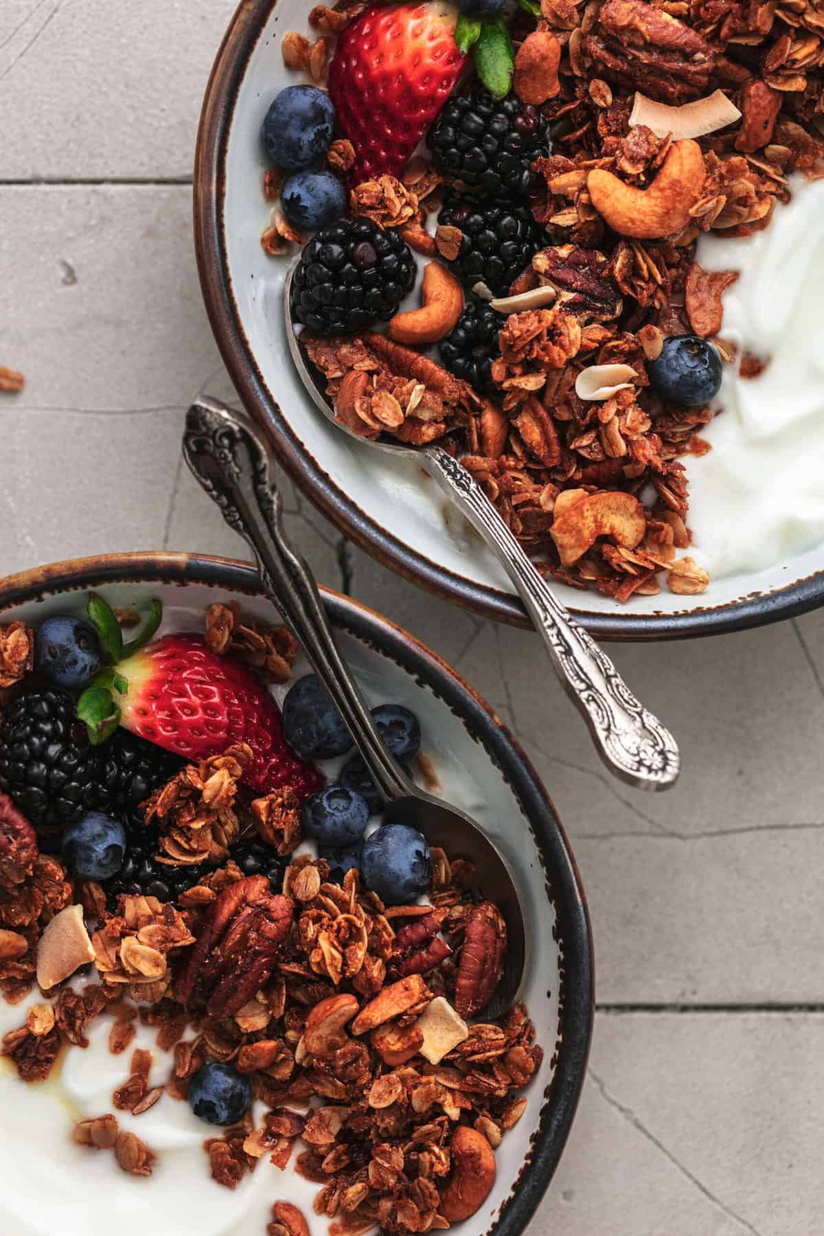 two bowls of yogurt with berries and nuts and oats