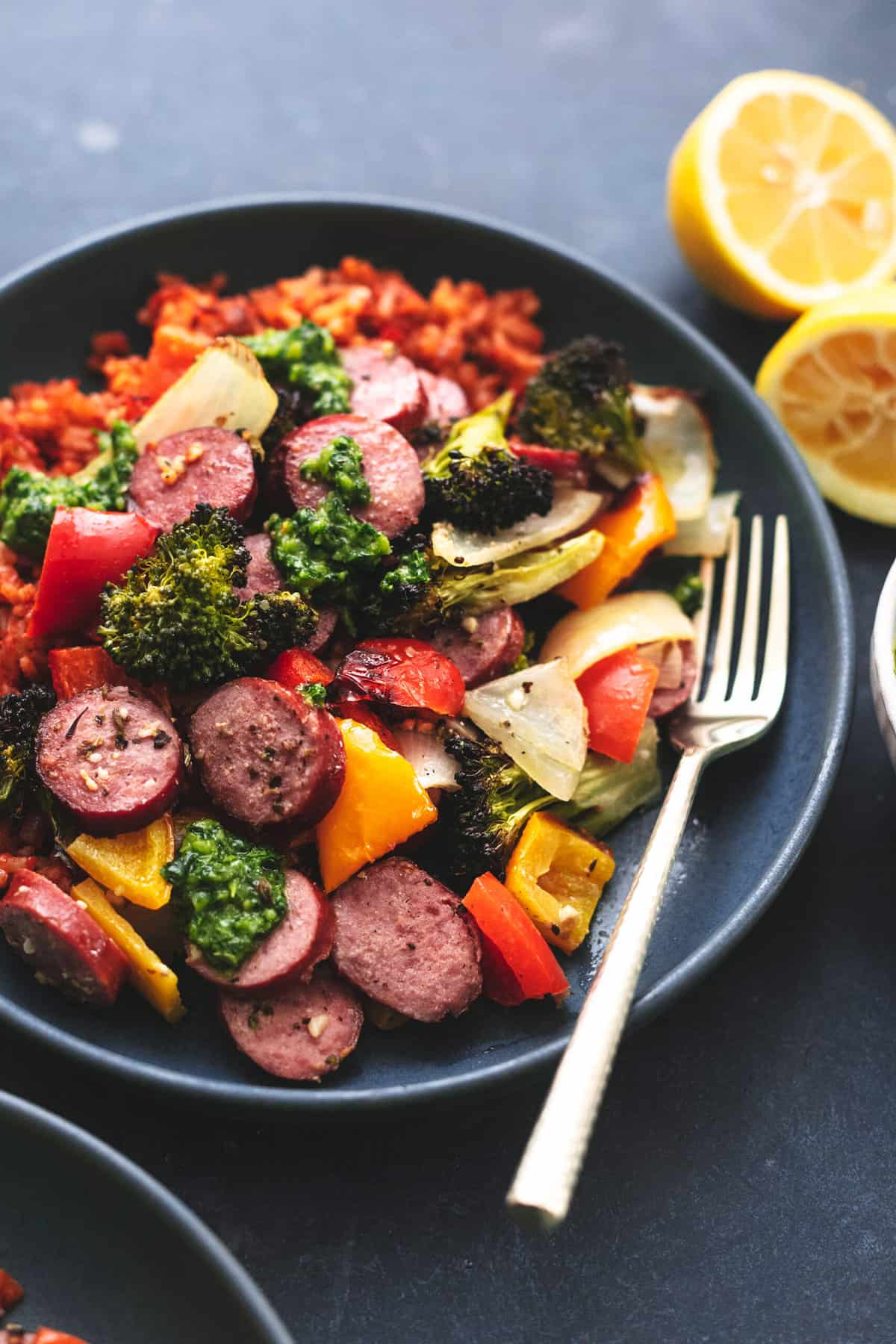 plate of roasted vegetables with sausage rounds and lemon halves