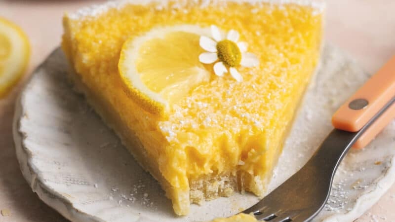 slice of lemon tart with bite missing on plate