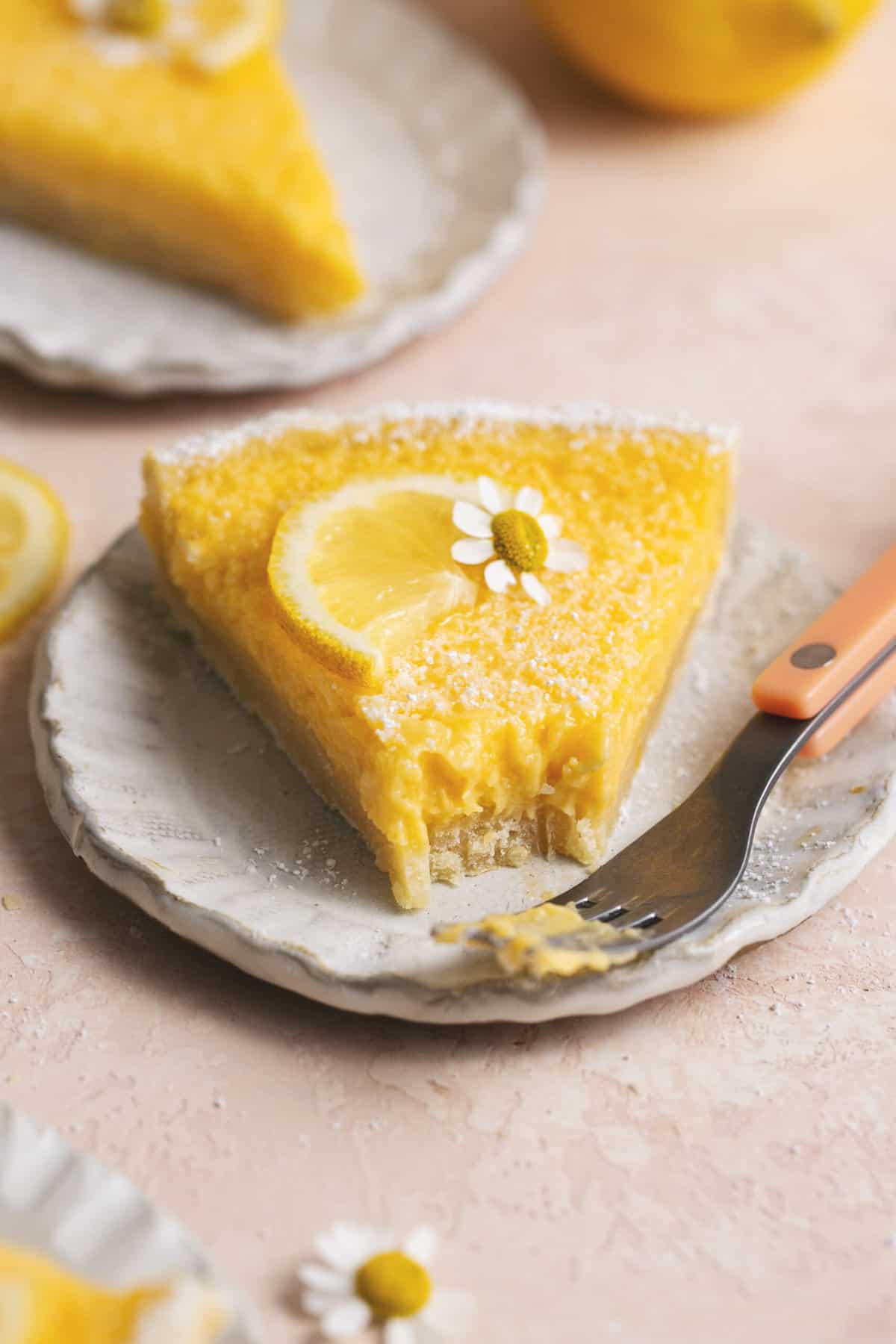 slice of lemon tart with bite missing on plate