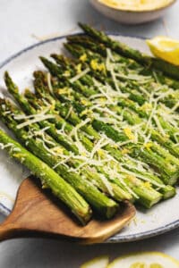 parmesan topped asparagus with serving spoon on platter