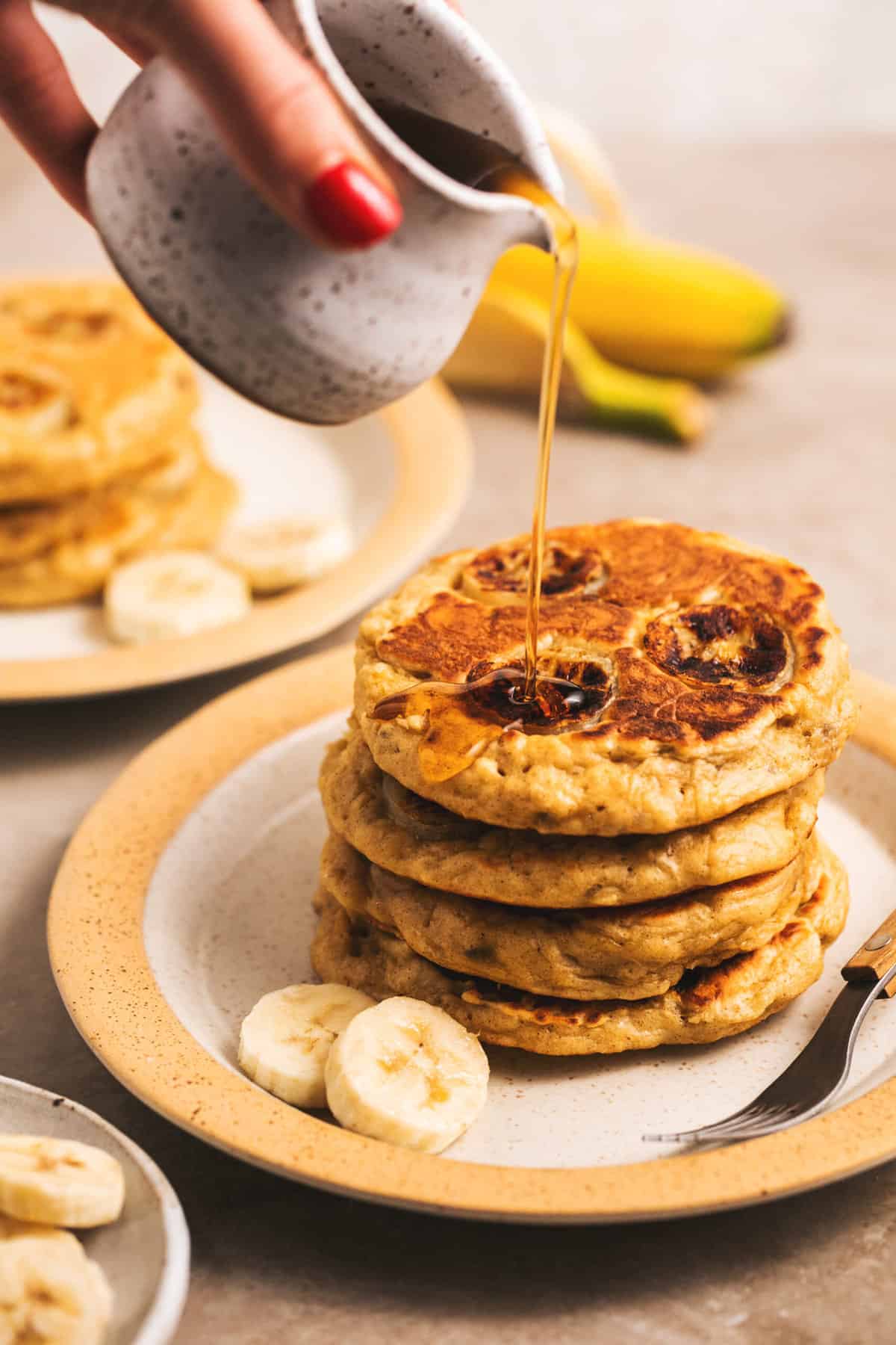 banana pancakes with syrup pouring on top 