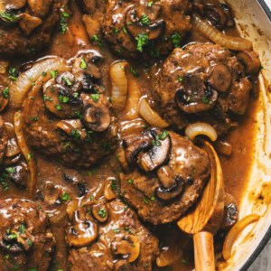 hamburger steaks in skillet with serving spoon