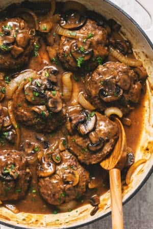 hamburger steaks in skillet with serving spoon