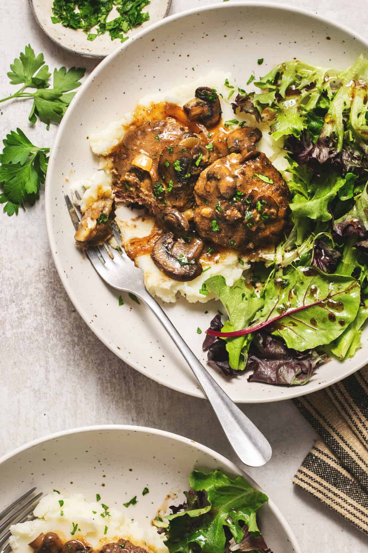 hamburger steaks with greens and fork on plate