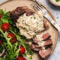 sliced steak on plate topped with blue cheese sauce