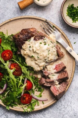 sliced steak on plate topped with blue cheese sauce