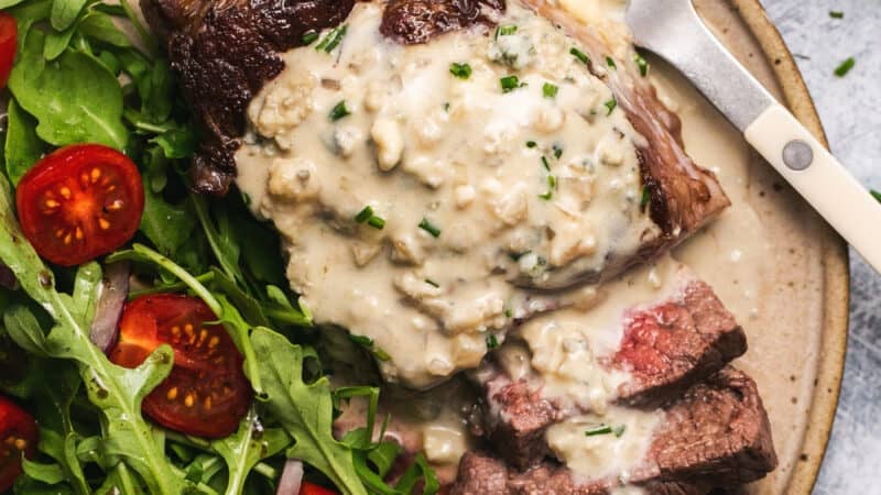 sliced steak on plate topped with blue cheese sauce