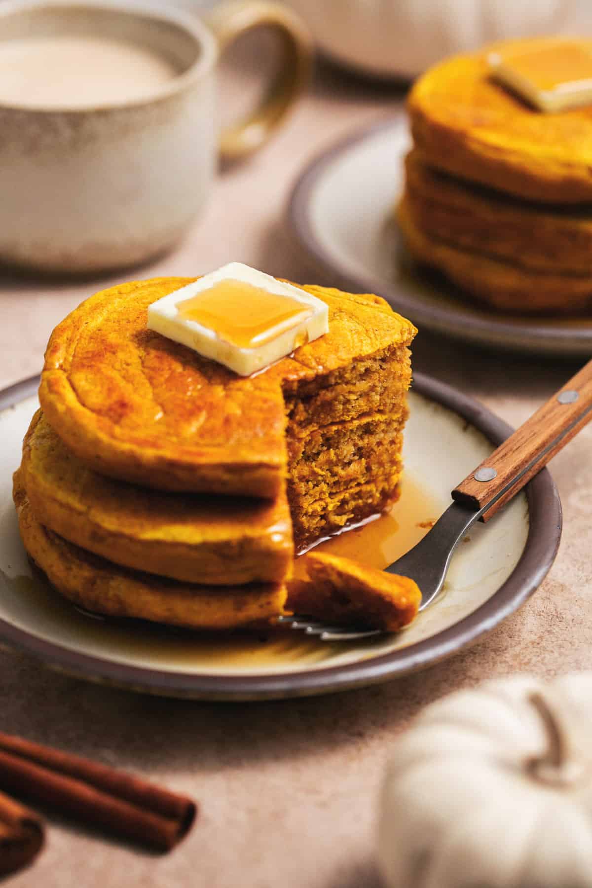 fork on plate with partially eaten pumpkin pancakes topped with syrup
