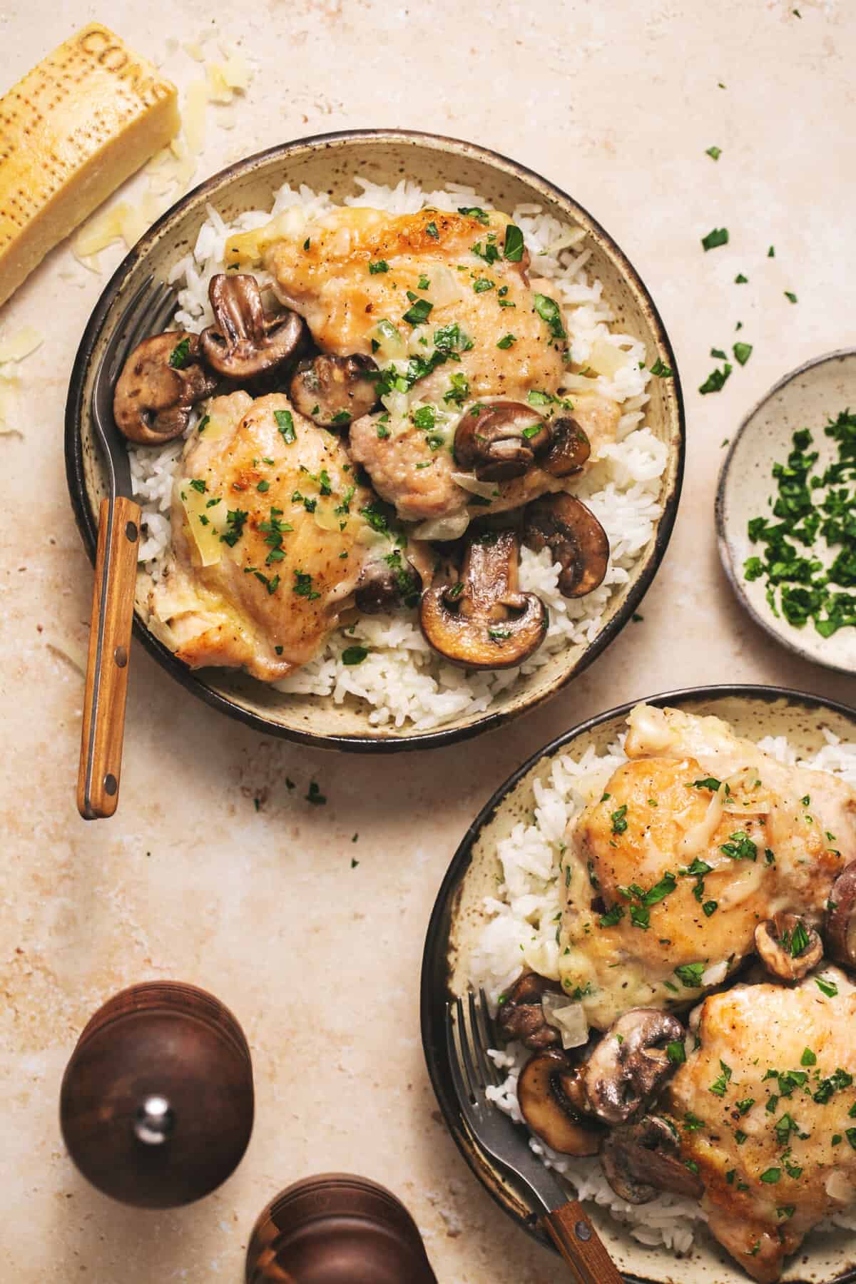 two plates with chicken and mushrooms with rice and forks